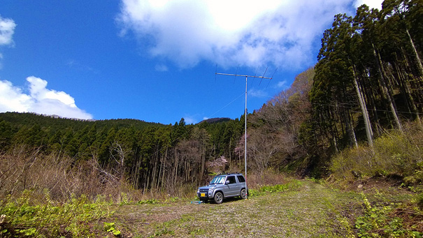 八峰町 池の台林道(F)。現地は坂になっていて、マストの垂直出しには タイヤベースの下に石をおいて傾きを調節。石はたくさんある。ただし ここに至る道路は かなりの悪路。まるで合成写真のような 青い空白い雲だけど、リアルだよ。